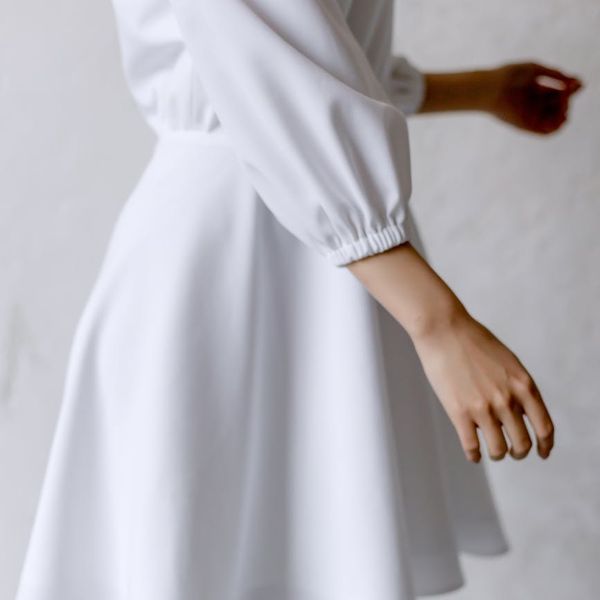 Woman performing a light, flowing movement in a bright, airy room.